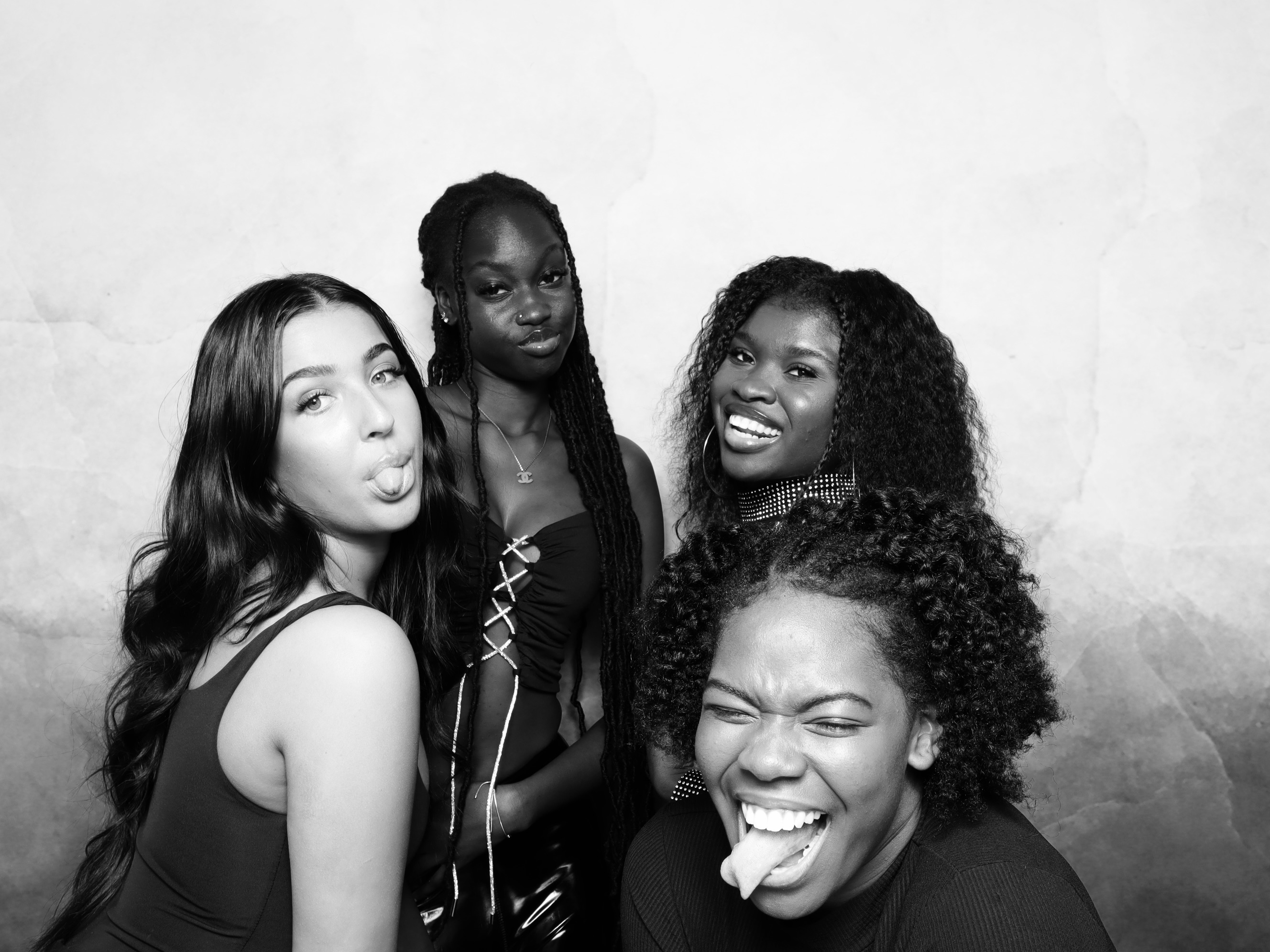 Four women striking playful poses at the Glam Booth with marble backdrop